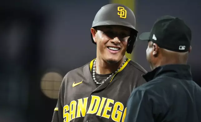 San Diego Padres' Manny Machado, back, jokes with first base umpire Alan Porter in the sixth inning of a baseball game against the Colorado Rockies Tuesday, April 21, 2026, in Denver. (AP Photo/David Zalubowski)