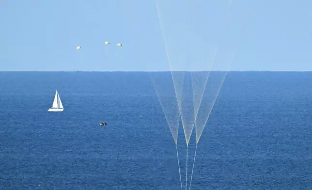 In this photo provided by NASA, NASA's Orion capsule descends under its main parachutes over the Pacific Ocean off the coast of California, following the Artemis II mission on Friday, April 10, 2026. (Josh Valcarcel/NASA via AP)