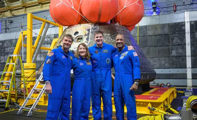 In this photo provided by NASA, from left, NASA astronauts Reid Wiseman, commander; Christina Koch, mission specialist; CSA (Canadian Space Agency) astronaut Jeremy Hansen, mission specialist; and NASA astronaut Victor Glover, Artemis II pilot, right, pose for a group photo after viewing the Orion spacecraft in the well deck of USS John P. Murtha, Saturday, April 11, 2026, in the Pacific Ocean off the coast of California. (Bill Ingalls/NASA via AP)