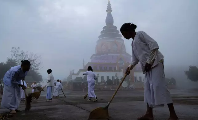 A group of women sweep the grounds of a pagoda in Tha Ton, Thailand, on Feb. 20, 2026. (AP Photo/Anton L. Delgado)