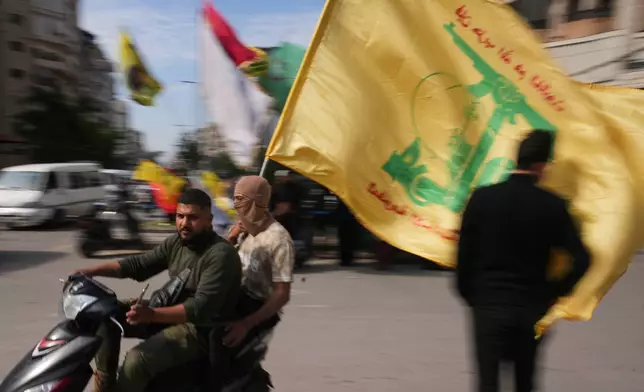 Men ride a scooter while waving a Hezbollah flag during a small gathering in Dahiyeh, Beirut's southern suburbs, Lebanon, Saturday, April 25, 2026. (AP Photo/Hassan Ammar)