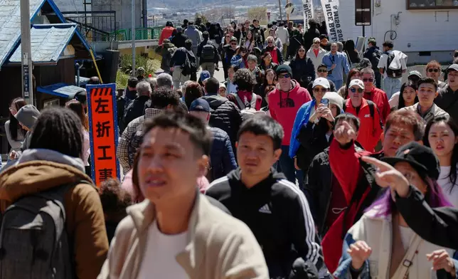 Foreign and Japanese visitors arrive to see cherry blossoms and Mount Fuji at Arakurayama Sengen Park on Wednesday, April 8, 2026, in Fujiyoshida, west of Tokyo. (AP Photo/Eugene Hoshiko)