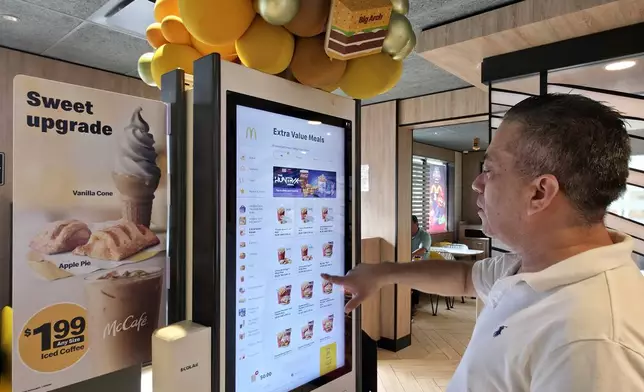 Carlos Paz picks a McValue menu selection at a McDonald's, Tuesday, March 31, 2026, in Los Angeles. (AP Photo/Damian Dovarganes)