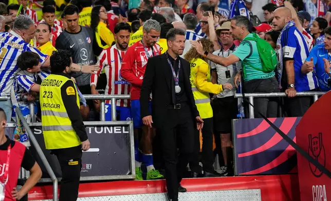 Atletico Madrid's head coach Diego Simeone, centre, and Atletico Madrid's Antoine Griezmann, centre left, walk with silver medals after the Copa del Rey final soccer match between Atletico Madrid and Real Sociedad in Seville, Spain, early Sunday, April. 19, 2026. (AP Photo/Jose Breton)