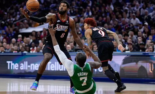 Philadelphia 76ers' Paul George (8) and Boston Celtics' Jaylen Brown (7) reach for a loose ball during the first half of Game 4 in a first-round NBA basketball playoffs series Sunday, April 26, 2026, in Philadelphia. (AP Photo/Matt Slocum)