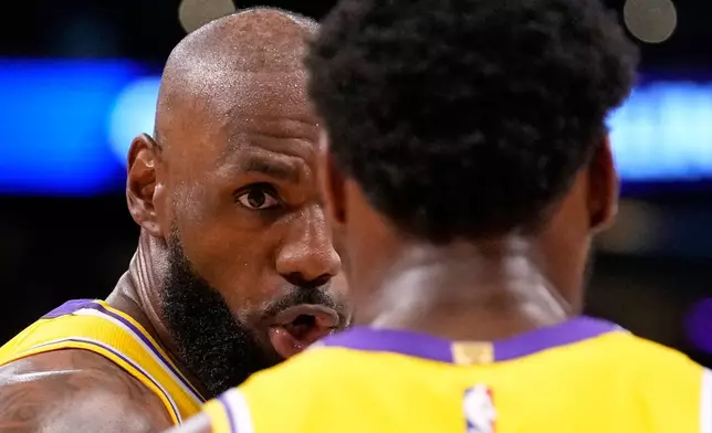 Los Angeles Lakers forward LeBron James, left, talks to guard Bronny James during the first half in Game 1 of a first-round NBA playoffs basketball series against the Houston Rockets, Saturday, April 18, 2026, in Los Angeles. (AP Photo/Mark J. Terrill)