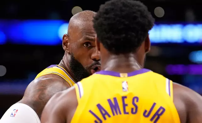 Los Angeles Lakers forward LeBron James, left, talks to his son guard Bronny James during the first half in Game 1 of a first-round NBA playoffs basketball series against the Houston Rockets, Saturday, April 18, 2026, in Los Angeles. (AP Photo/Mark J. Terrill)