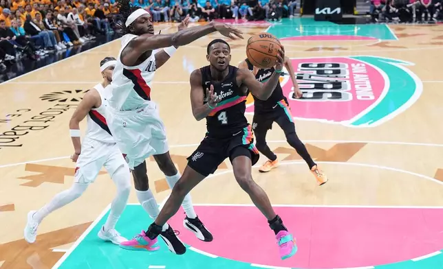 San Antonio Spurs guard De'aaron Fox (4) drives to the basket past Portland Trail Blazers forward Jerami Grant, left, during the second half in Game 1 of a first-round NBA playoffs basketball series in San Antonio, Sunday, April 19, 2026. (AP Photo/Eric Gay)
