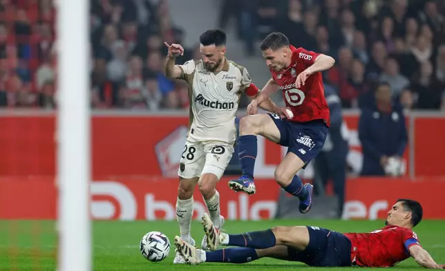 Lens' Adrien Thomasson, left, and Lille's Aissa Mandi, down, challenge for the ball during the French League One soccer match between Lille and Lens, in Lille, France, Saturday, April 4, 2026. (AP Photo/Jean-Francois Badias)