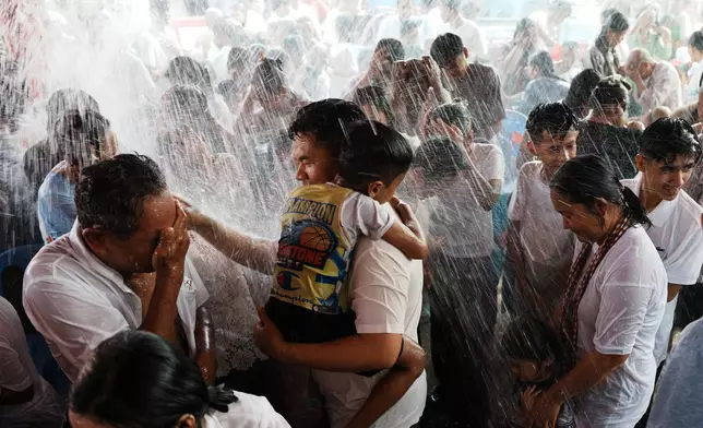 Local residents of Prey Popel village receive a holy water shower, which is believed to bring good luck, during Khmer New Year celebrations on the outskirts of Phnom Penh, Cambodia, Sunday, April 12, 2026. (AP Photo/Heng Sinith)