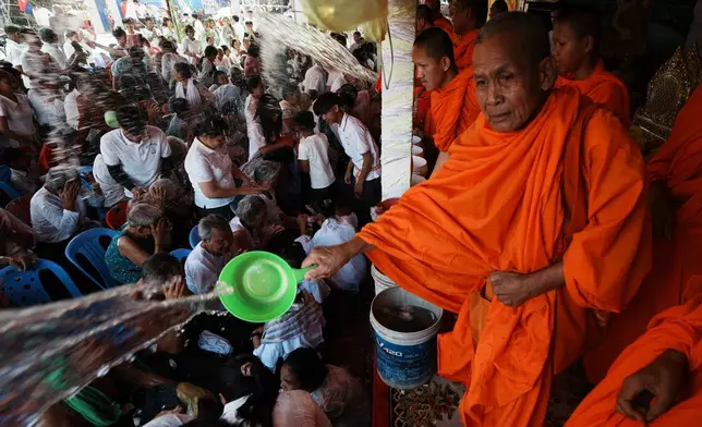 Local residents of Prey Popel village receive holy water from Buddhist monks, right, a ritual believed to bring good luck, during Khmer New Year celebrations on the outskirts of Phnom Penh, Cambodia, Sunday, April 12, 2026. (AP Photo/Heng Sinith)