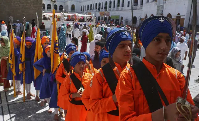 Sikh youth, in traditional dress and holding ceremonial swords, attend a ceremony to celebrate Vaisakhi festival, which also marks the New Year in Sikh tradition, at the shrine of Gurdwara Punja Sahib, the second most sacred place for Sikhs, in Hassan Abdal, Pakistan, Tuesday, April 14, 2026. (AP Photo/Anjum Naveed)