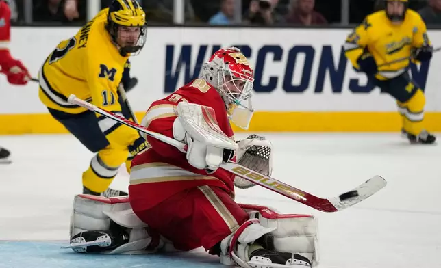 Denver goaltender Johnny Hicks (31) knocks the puck away against Michigan in overtime of a semifinal game in the NCAA Frozen Four men's college hockey tournament Thursday, April 9, 2026, in Las Vegas. (AP Photo/John Locher)