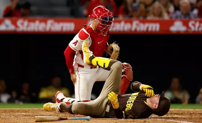 San Diego Padres' Jake Cronenworth, bottom, reacts after getting hit with a pitch during the fifth inning of a baseball game against the Los Angeles Angels, Saturday, April 18, 2026, in Anaheim, Calif. (AP Photo/Caroline Brehman)