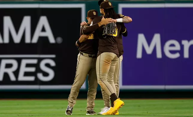 San Diego Padres left fielder Ramon Laureano (5), from left, San Diego Padres right fielder Fernando Tatis Jr. (23) and San Diego Padres center fielder Jackson Merrill (3) embrace upon defeating the Los Angeles Angels at the end of the ninth inning of a baseball game, Saturday, April 18, 2026, in Anaheim, Calif. (AP Photo/Caroline Brehman)