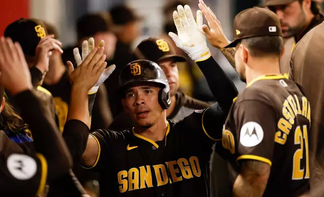 San Diego Padres' Freddy Fermin (54) is greeted by teammates after scoring during the eighth inning of a baseball game against the Los Angeles Angels, Saturday, April 18, 2026, in Anaheim, Calif. (AP Photo/Caroline Brehman)