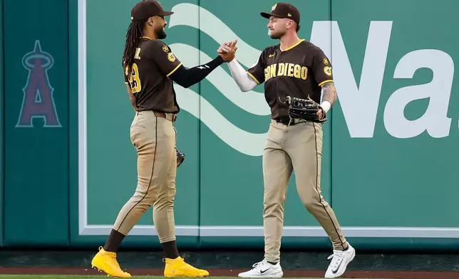 San Diego Padres center fielder Jackson Merrill (3) is greeted by San Diego Padres right fielder Fernando Tatis Jr. (23) after catching a ball hit by Los Angeles Angels' Yoan Moncada (10) during the second inning of a baseball game Saturday, April 18, 2026, in Anaheim, Calif. (AP Photo/Caroline Brehman)