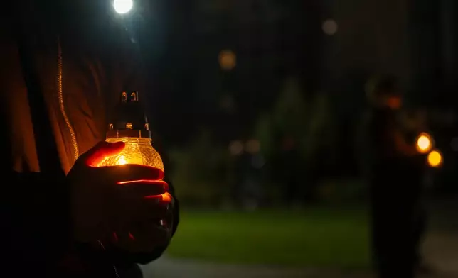 People bring candles at a memorial dedicated to firefighters and workers who died after the 1986 Chornobyl (Chernobyl) nuclear disaster, ahead of its 40th anniversary in Slavutych, Ukraine, Saturday, April 25, 2026. Chornobyl is the Ukrainian name for the city. (AP Photo/Dan Bashakov)