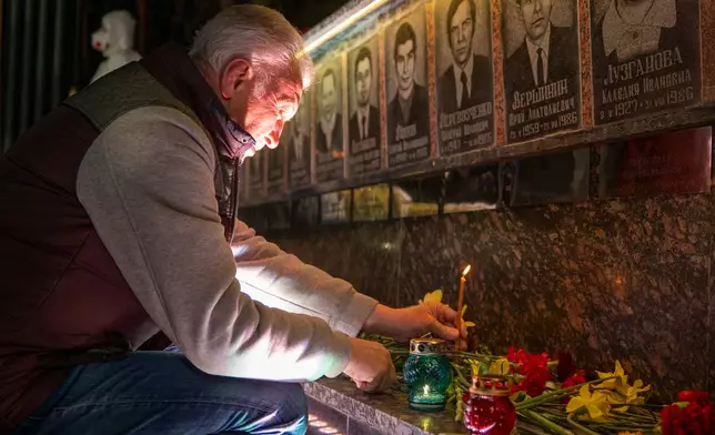 A man lights a candle at a memorial dedicated to firefighters and workers who died after the 1986 Chornobyl (Chernobyl) nuclear disaster, ahead of its 40th anniversary in Slavutych, Ukraine, Saturday, April 25, 2026. Chornobyl is the Ukrainian name for the city. (AP Photo/Dan Bashakov)