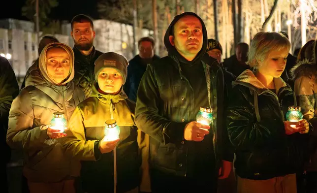People bring candles at a memorial dedicated to firefighters and workers who died after the 1986 Chornobyl (Chernobyl) nuclear disaster, ahead of its 40th anniversary in Slavutych, Ukraine, Saturday, April 25, 2026. Chornobyl is the Ukrainian name for the city. (AP Photo/Dan Bashakov)