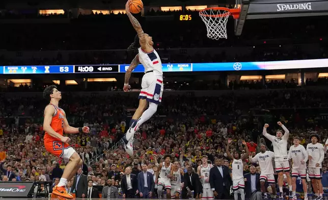 UConn's Solo Ball (1) dunks as Illinois' Andrej Stojakovic, left, watches during the second half of an NCAA college basketball tournament semifinal game at the Final Four, Saturday, April 4, 2026, in Indianapolis. (AP Photo/Michael Conroy)