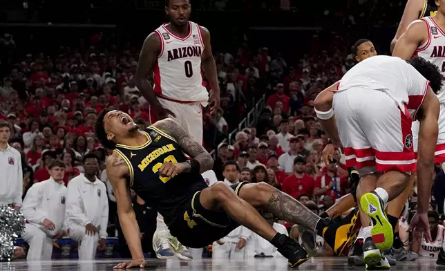 Michigan forward Yaxel Lendeborg (23) falls after play against Arizona during the first half of an NCAA college basketball tournament semifinal game at the Final Four, Saturday, April 4, 2026, in Indianapolis. (AP Photo/Abbie Parr)