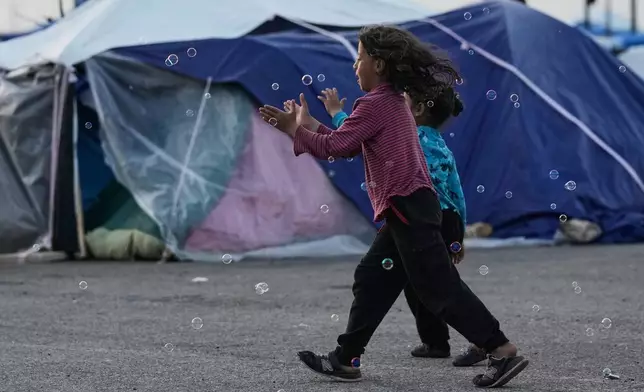 Girls chase bubbles next to their family's tents used as shelter after fleeing Israeli bombardment in Dahiyeh, Beirut's southern suburbs, in Beirut, on Wednesday, April 15, 2026. (AP Photo/Bilal Hussein)