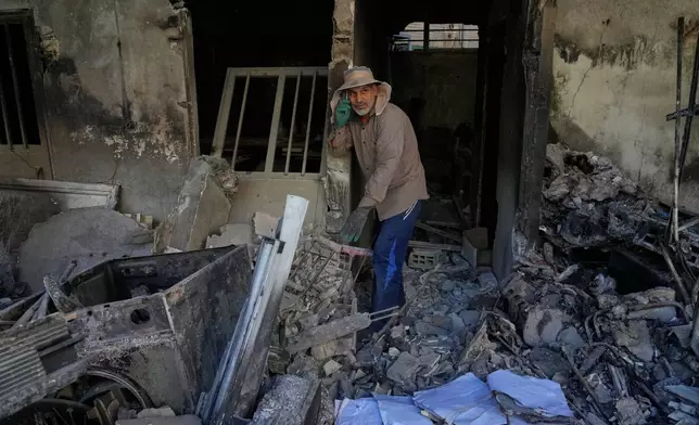 A volunteer talks on his phone while walking amid the debris of a residential building that, according to the authorities, was damaged on March 4 during the U.S.-Israeli military campaign, in southeastern Tehran, Iran, Tuesday, April 14, 2026. (AP Photo/Vahid Salemi)