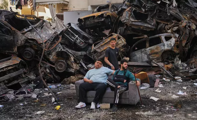 Residents sit on a sofa in front of charred cars at the site of a building destroyed in an Israeli airstrike last Wednesday in central Beirut, Lebanon, Tuesday, April 14, 2026. (AP Photo/Hassan Ammar)