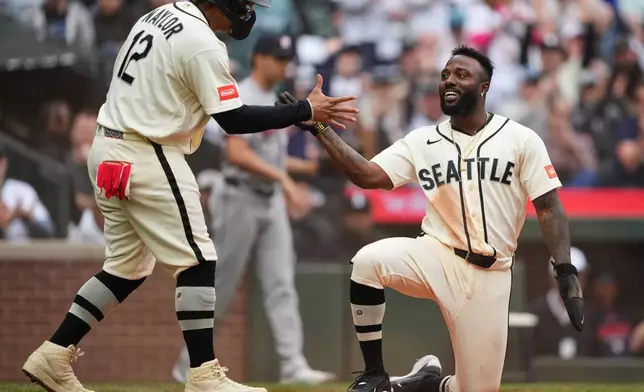 Seattle Mariners' Josh Naylor greets Randy Arozarena, right, after they scored on a two-run double from Luke Raley against the Houston Astros during the sixth inning of a baseball game, Sunday, April 12, 2026, in Seattle. (AP Photo/Lindsey Wasson)