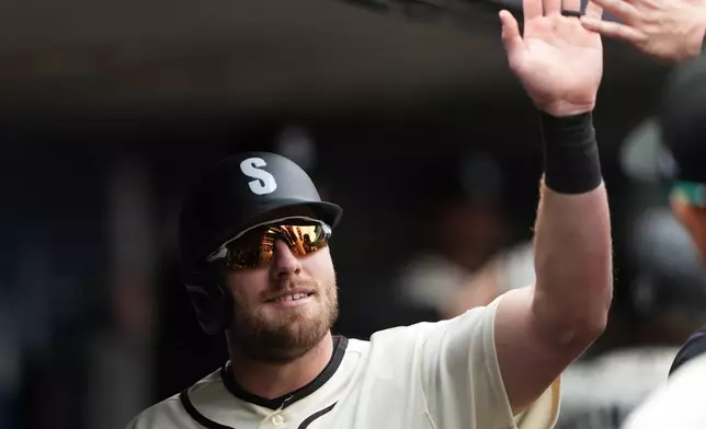 Seattle Mariners' Luke Raley celebrates in the dugout after scoring on a sacrifice fly from Mariners' Brendan Donovan during the third inning of a baseball game against the Houston Astros, Sunday, April 12, 2026, in Seattle. (AP Photo/Lindsey Wasson)