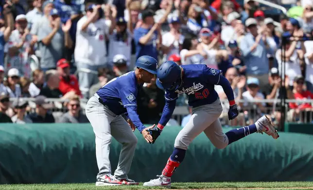 Los Angeles Dodgers' Mookie Betts. low-fives third base coach Dino Ebel after hitting a two-run home run against Washington Nationals during the third inning of an baseball game, Friday, April 3, 2026, in Washington. (AP Photo/Terrance Williams)