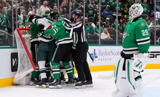 Dallas Stars goaltender Jake Oettinger, right, skates away as teammates and Minnesota Wild players fight in the second period of an NHL hockey game Thursday, April 9, 2026, in Arlington, Texas. (AP Photo/Tony Gutierrez)