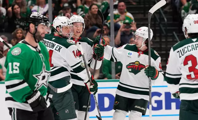Minnesota Wild's Joel Eriksson Ek (14), Kirill Kaprizov, center rear, and Quinn Hughes (43) celebrate in front of Dallas Stars' Colin Blackwell (15) after Kaprizov scored in the second period of an NHL hockey game Thursday, April 9, 2026, in Arlington, Texas. (AP Photo/Tony Gutierrez)