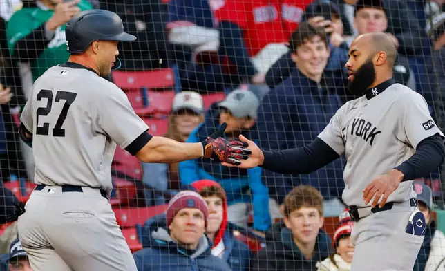 New York Yankees' Giancarlo Stanton, left, is greeted by Amed Rosario, right, after Stanton hit a solo home run during the second inning of a baseball game against the Boston Red Sox on Tuesday, April 21, 2026, in Boston. (AP Photo/CJ Gunther)