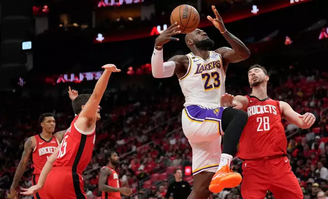 Los Angeles Lakers forward LeBron James (23) goes to the basket against Houston Rockets' Reed Sheppard, left, and Alperen Sengun (28) during the first half in Game 4 of a first-round NBA basketball playoffs series, Sunday, April 26, 2026, in Houston. (AP Photo/Karen Warren)