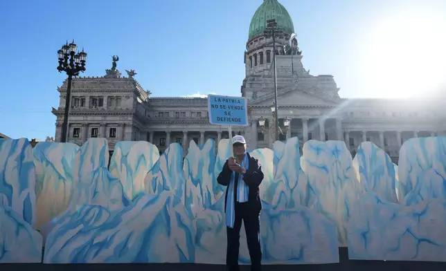A demonstrator holds a banner that reads in Spanish, "The homeland is not for sale, it's defended" as lawmakers debate the Javier Milei government's proposal to reform the glacier protection law, outside Congress in Buenos Aires, Argentina, Wednesday, April 8, 2026. (AP Photo/Rodrigo Abd)