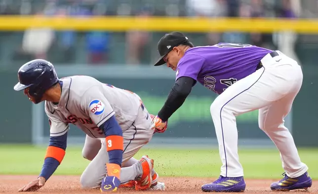 Colorado Rockies shortstop Ezequiel Tovar, right, tags out Houston Astros' Jeremy Pena at second base on the back end of a double play hit into by Yordan Alvarez in the first inning of a baseball game Tuesday, April 7, 2026, in Denver. (AP Photo/David Zalubowski)