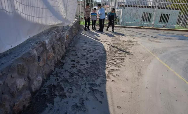 Children look at a damaged play ground hit yesterday by projectiles launched from Lebanon in Nahariya, northern Israel, Sunday, April 12, 2026. (AP Photo/Ariel Schalit)