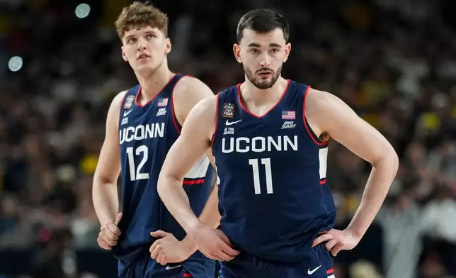 UConn forward Alex Karaban (11) and center Eric Reibe looks towards the bench during the first half of the NCAA college basketball tournament national championship game against Michigan at the Final Four, Monday, April 6, 2026, in Indianapolis. (AP Photo/Abbie Parr)