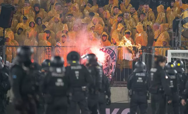 Police officers stand in front of the K-Block section with Dresden fans during a stoppage in play in the Bundesliga 2 soccer match between Dynamo Dresden and Hertha BSC, Saturday, April 4, 2026, in Dresden, Germany. (Sebastian Kahnert/dpa via AP)