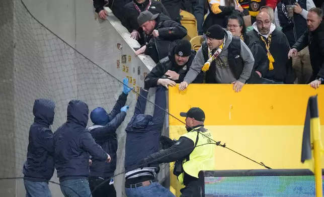 Hertha BSC fans, left, and Dresden fans scuffle during a Bundesliga 2 soccer match between Dynamo Dresden and Hertha BSC, Saturday, April 4, 2026, in Dresden, Germany. (Sebastian Kahnert/dpa via AP)