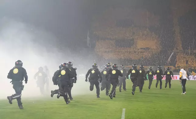 Law enforcement personnel run onto the pitch during a stoppage in play in the Bundesliga 2 soccer match between Dynamo Dresden and Hertha BSC, Saturday, April 4, 2026, in Dresden, Germany. (Sebastian Kahnert/dpa via AP)