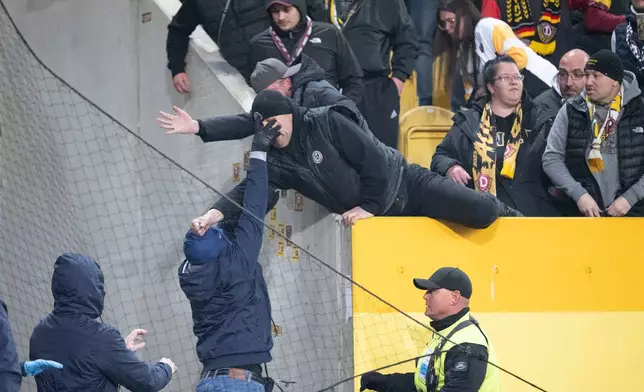 Hertha BSC fans, left, and Dresden fans scuffle during a Bundesliga 2 soccer match between Dynamo Dresden and Hertha BSC, Saturday, April 4, 2026, in Dresden, Germany. (Sebastian Kahnert/dpa via AP)