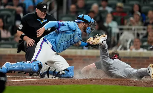 Cleveland Guardians' Daniel Schneemann (10) is safe at home plate against Atlanta Braves catcher Jonah Heim (20) inning of a baseball game, Saturday, April 11, 2026, in Atlanta. (AP Photo/Mike Stewart)