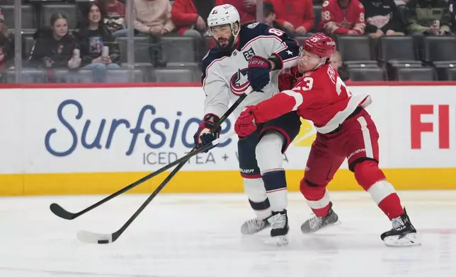Columbus Blue Jackets right wing Kirill Marchenko (86) shoots as Detroit Red Wings left wing Lucas Raymond (23) defends in the first period of an NHL hockey game Tuesday, April 7, 2026, in Detroit. (AP Photo/Paul Sancya)