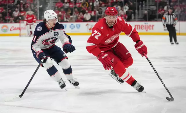 Detroit Red Wings defenseman Justin Faulk (72) protects the puck from Columbus Blue Jackets center Kent Johnson (91) in the second period of an NHL hockey game Tuesday, April 7, 2026, in Detroit. (AP Photo/Paul Sancya)