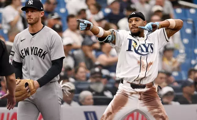 New York Yankees third baseman Ryan McMahon, left, looks away after Tampa Bay Rays' Chandler Simpson, right, slid into third base for a triple during the seventh inning of a baseball game Sunday, April 12, 2026, in St. Petersburg, Fla. (AP Photo/Jason Behnken)