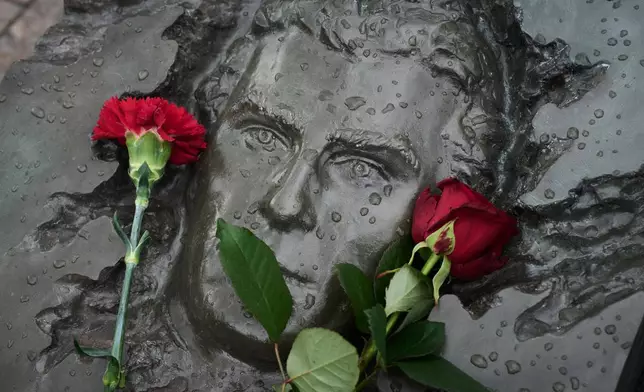 Red flowers lie on a bas-relief of firefighter Georgy Popov atop of his grave at the Mitinskoye Cemetery where several victims of the Chernobyl nuclear disaster are buried, marking the 40th anniversary of the explosion and fire at the Chernobyl nuclear power plant in Ukraine, outside Moscow, Sunday, April 26, 2026. (AP Photo/Alexander Zemlianichenko)