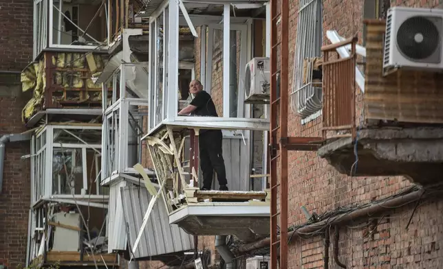 A man stands at a balcony of a residential building damaged by a Russian strike on Dnipro, Ukraine, Saturday, April 25, 2026. (AP Photo/Mykola Synelnykov)